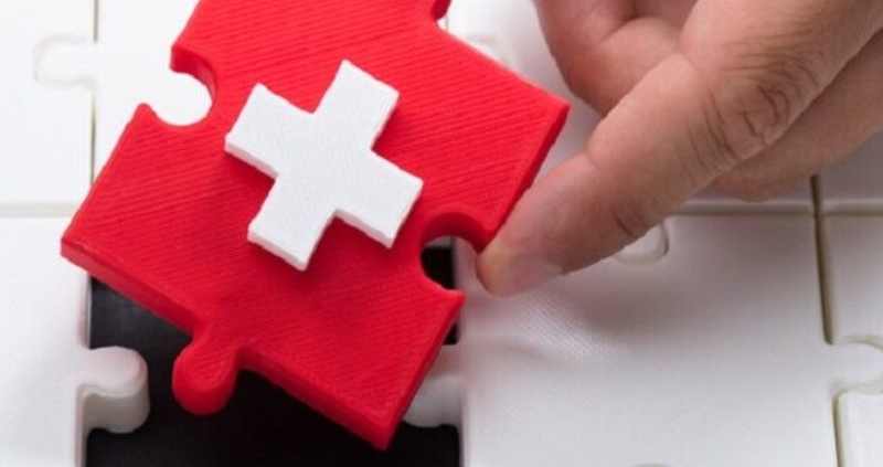 white medical cross on red puzzle piece_canstockphoto59692997-2-800x533