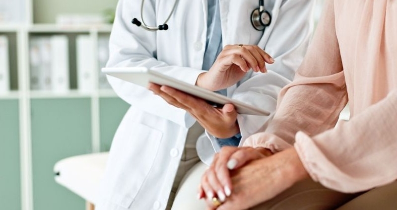 clinic, tablet and hands of doctor with patient_shutterstock_2472677019 800x533
